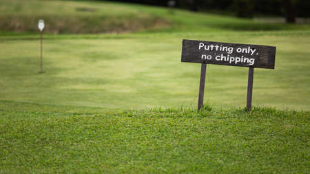 A sign on a wooden bench sitting in the middle of a fieldの写真素材