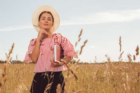 Portrait beautiful girl reading a book in the fieldの写真素材