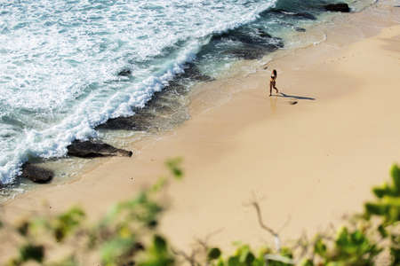 beautiful girl walks along the wild beachの写真素材