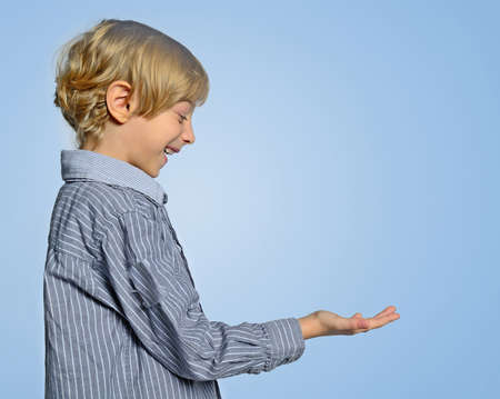 Young boy holding empty palm on blue backgroundの写真素材