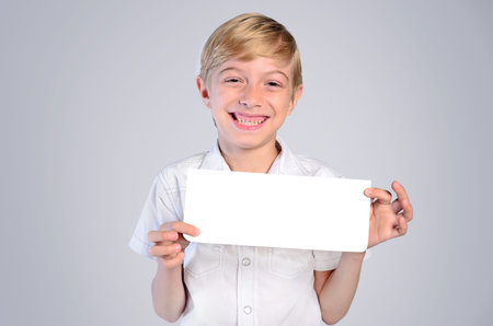 Young child boy with card on grey backgroundの写真素材