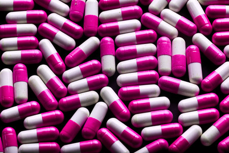 Many pink and white capsules. Background of pink tablets. Medications.