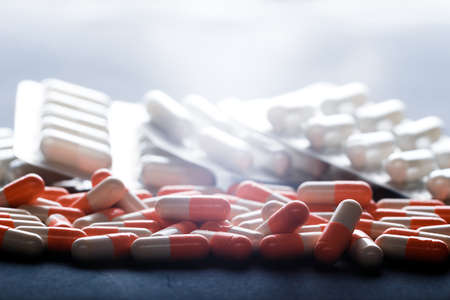 Background of tablets. Many orange capsules. Medications. Medicine Pills. Many different colorful medication and pills from above on black background. Pills in strips.の写真素材