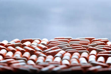 Many medicine orange and white capsules. Background of orange tablets. Medications. Pink pills. Abstract pharmaceutics background.の写真素材