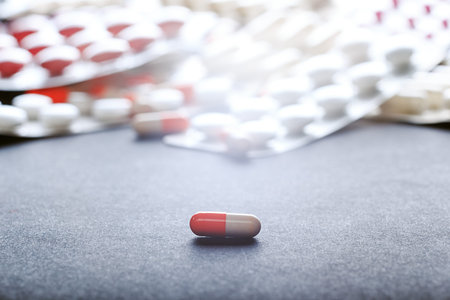 Single orange-white capsule. Single tablet on background with many medicine orange and white...