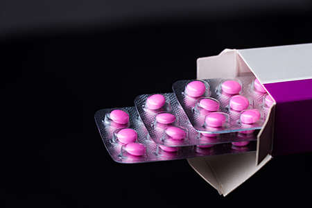 Pinkl pills in strips and in paper packaging. Medications. Medicine pink Pills. Medicine background from three strips of pink pills on black background.の写真素材