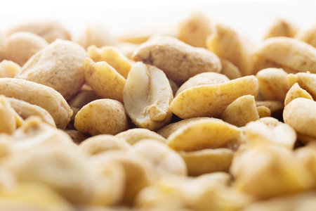 Fried salted nuts peanuts on a white background in a plate. Assorted snack pile of nuts. Abstract...