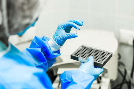 A woman in a sterile lab coat holds in her hand a medical tablet with drugs in white sterile medical gloves.の写真素材