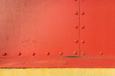 Red and yellow vintage industrial texture with symmetrical horizontal and vertical metal rivets