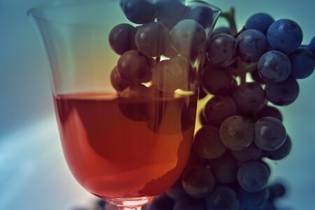 Red wine in wine glass with grapes.Selective Focus, Focus on the front of the rim of the wine glassの写真素材