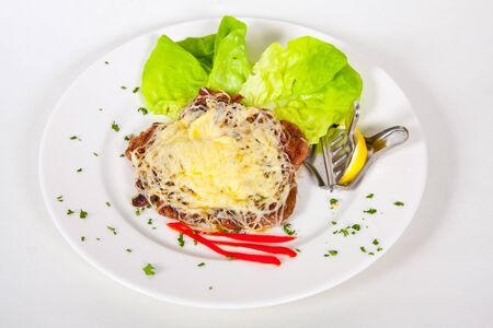 French meat baked in cheese with herbs and lemon on a plateの写真素材