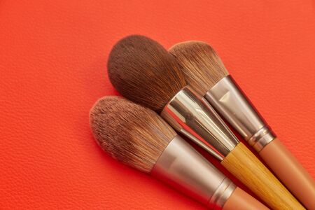 Brushes and tools for makeup and skin care lie on an isolated orange background. Place for textの写真素材