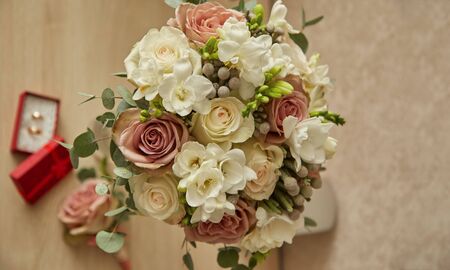 Wedding rings and beautiful wedding bouquet on natural wooden desk with nature in background.の写真素材