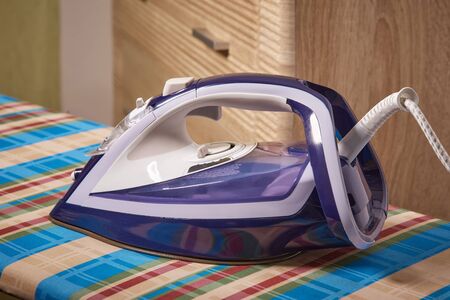 Functional modern iron on the Ironing Board on multi-colored backgroundの写真素材
