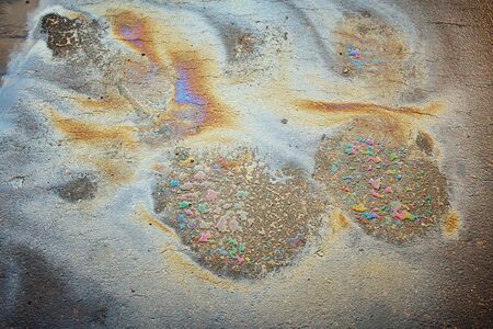 Oil stain on Asphalt road after rain. Multi-colored poisonous spots on the parking. Multi-colored oil stain on the pavement.の写真素材
