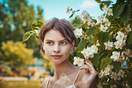Attractive modest young woman natural makeup in a white dress outdoors, tenderness and softness against the background of natureの写真素材