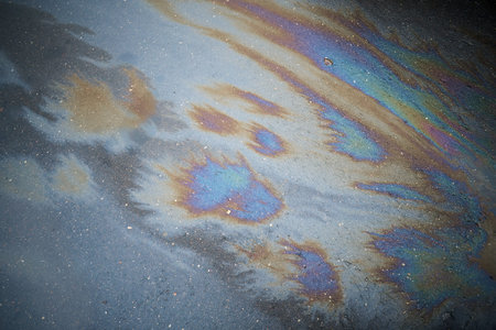 Abstract rainbow effect, colorful gas stain on wet asphalt. Rainbow gasoline leak after a car on a...