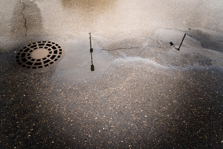 Oil slick on the asphalt road background drains into the storm drain.Water pollution environmental...