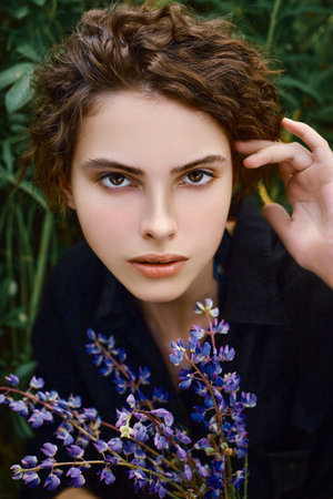 Vertical portrait of a young woman with a bouquet of lupines in her handの写真素材