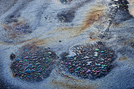 Oil stain on wet asphalt caused by a leak under a car or truck