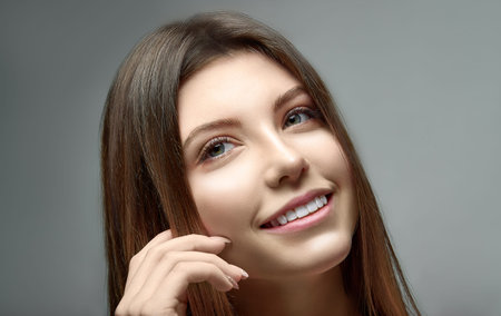 Beautiful young woman portrait, Smiling cute girl with long hair studio shot, Isolated on gray...