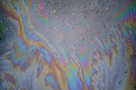 Colored oil stains in the car park, the color of the gasoline stain on the pavement road as a texture or background. Abstract rainbow effect backgroundの写真素材