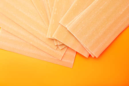 Raw lasagna pasta on orange background fanned outの写真素材