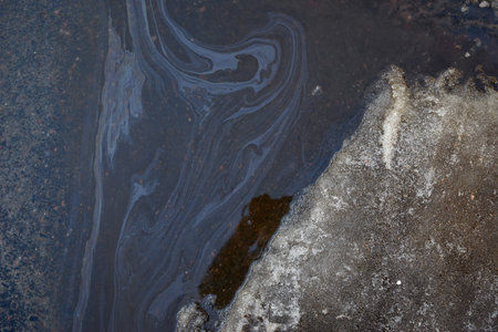 Rainbow spots of gasoline and gas near the car.