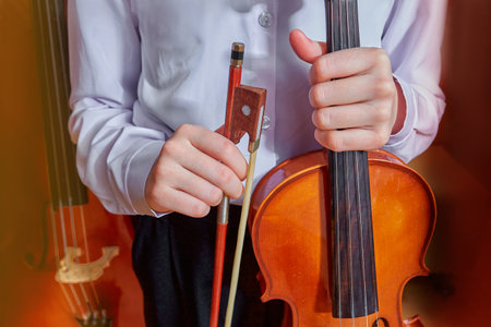 childrens hands hold a violin and a bow