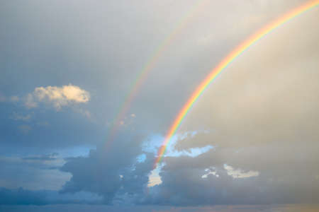 Beautiful rainbow after after rain in the blue sky with clouds.の写真素材