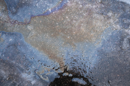 Melting snow with rainbow stains of spilled gasoline and oil on the asphalt. Environmental pollution conceptの写真素材