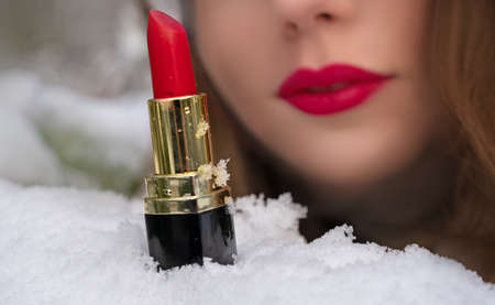 lipstick on the snow against the background of a young woman's face out of focusの写真素材