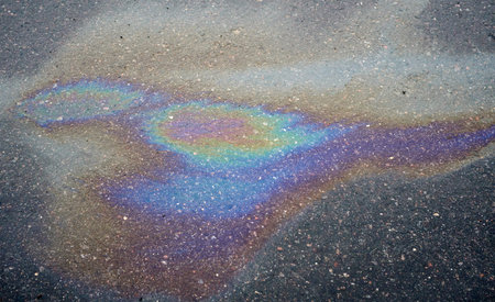 Colored spots of oil or gasoline on the asphalt as a texture or background. Environmental pollution...
