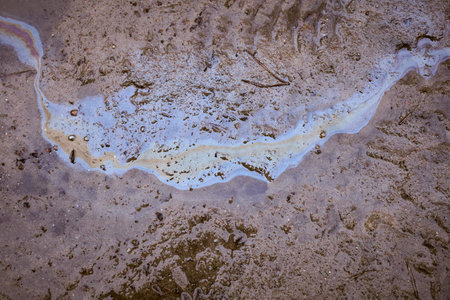 Gasoline or oil on the background of a puddle on a country dirt road