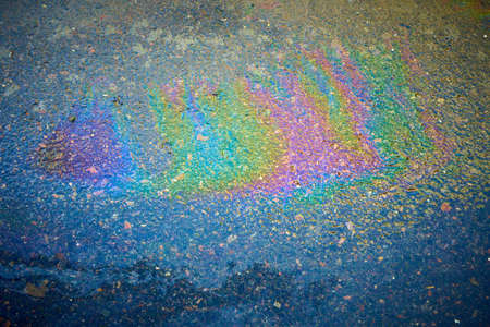 Oil stain on an asphalt road in a puddle in sunlight. Colored spots of gasoline on an asphalt roadの写真素材