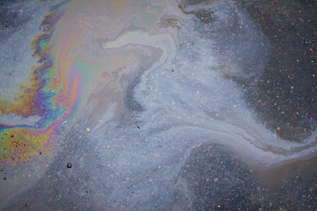 Oil stain on the asphalt,-shaped colored gasoline stains on an rainbow asphalt road as a texture or backgroundの写真素材