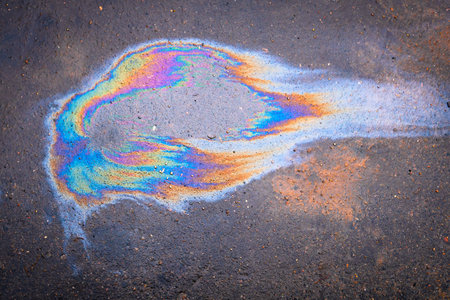 Spills of fuel or oil on the asphalt road as texture or background. Spot in the form of a cat's head.の写真素材