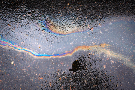 Oil stain on the asphalt,-shaped colored gasoline stains on an rainbow asphalt road as a texture or...