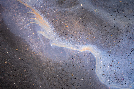 Gasoline stain on the roadway. Oil petrol water pollution.