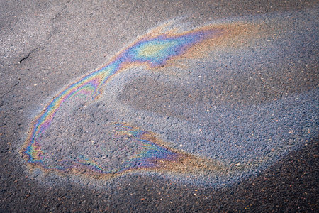 Dirty multi-colored stain from engine oil on asphalt. environmental pollution concept.の写真素材
