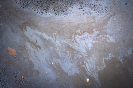 Dirty multi-colored stain from engine oil on asphalt. Environmental pollution concept.の写真素材
