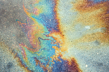 Texture of colorful petrol oil spill on wet pavement. Petrol Oil Pollution Rainbow Gasoline Leak on Pavementの写真素材