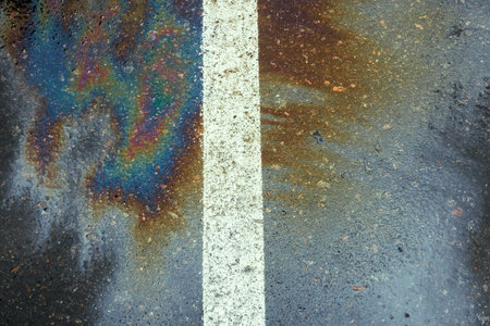 Oil spill on dark wet asphalt, parking lot with dividing lines.の写真素材