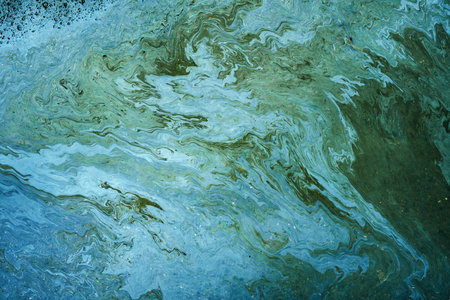Marble texture of rainbow gasoline spill on the sidewalk in a puddle as a background.の写真素材