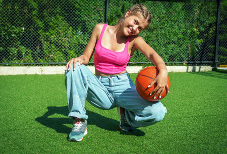 Portrait of a young woman playing basketball on a green artificial turfの写真素材