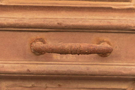 A fragment of an old wooden door with a metal handle covered with rust.の写真素材