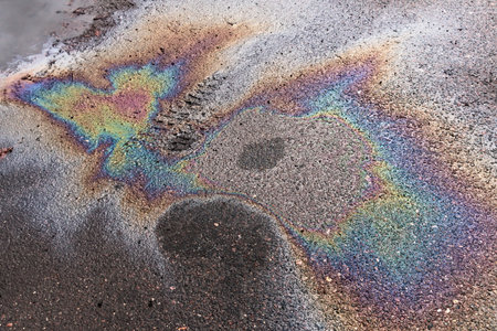 Abstract colored background of gasoline leak on wet asphalt with marks from boots.の写真素材