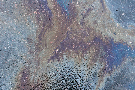 Textured stain of fuel or oil on wet asphalt on a rainy day. The concept of environmental pollution.