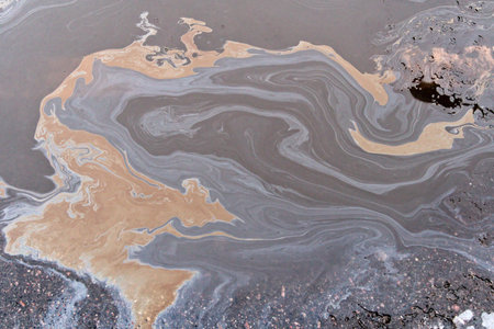 A marble texture of a rainbow spill of gasoline on a sidewalk in a puddle as a background.