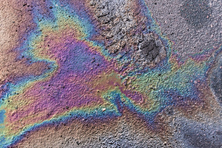 Gasoline spot on wet asphalt. Multi colored oil spill on asphalt road, abstract background, texture....